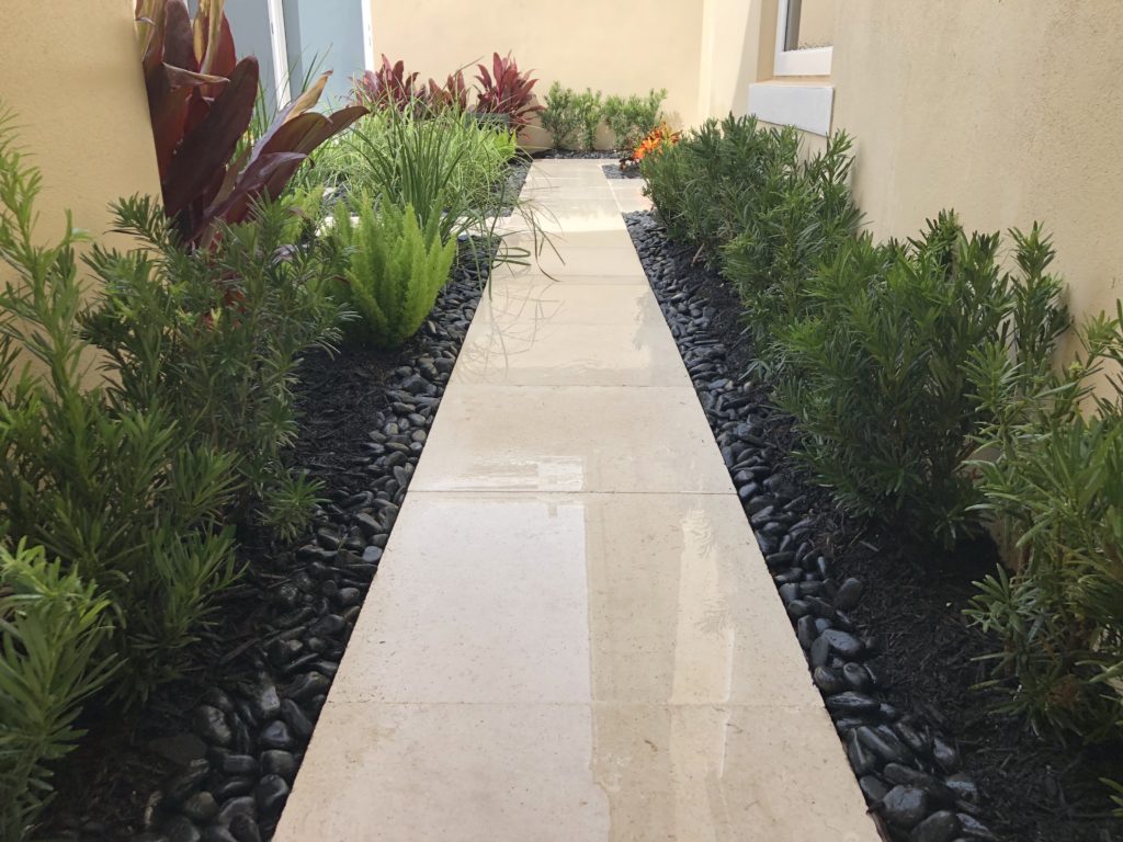 A travertine tile walkway with mulch and rock
